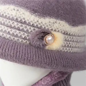 Close-up of knit winter hat featuring a faux pearl brooch and soft plush texture