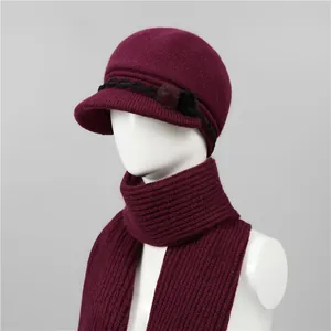 Detalle del conjunto de gorro y bufanda de punto burdeos con pompones en un maniquí