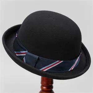 Detail of a vintage black wool bowler hat with a striped ribbon on a wooden stand