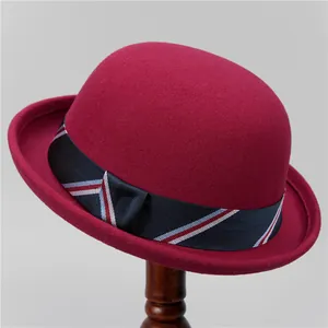 Detail of vintage burgundy wool felt bowler hat with a striped ribbon trim and rolled brim
