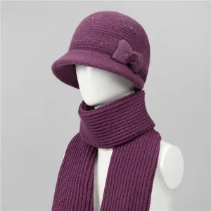 Detalle del conjunto de gorro y bufanda de punto violeta oscuro con lazo y cuentas