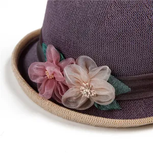 Detailansicht eines lila Webhutes mit eleganten Satinblumen und Strohumrandung