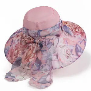 Detail view of the wide-brimmed pink sun hat featuring floral prints and a large silk bow