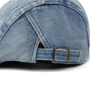 Detail einer hellblauen Jeans-Baskenmütze mit verstellbarer Metallschnalle und Naht