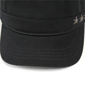 Detail of black cotton flat top cap featuring metal star rivets and reinforced stitching