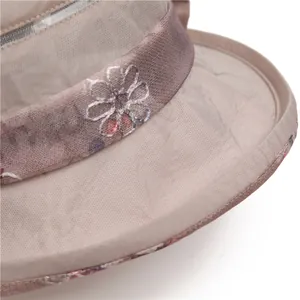 Nahaufnahme eines eleganten Organza-Sonnenhutes mit weißer Stickerei und Satinband-Detail
