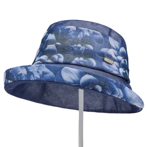 Detail of blue floral organza sun hat featuring a metal 'FASHION' tag and breathable fabric