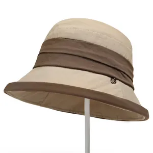Macro shot of khaki cloche sun hat with dark brown ribbon and metallic detail