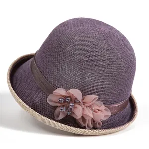 Detail eines lila Strickhuts mit Organza-Blumendekoration und eleganten Perlen