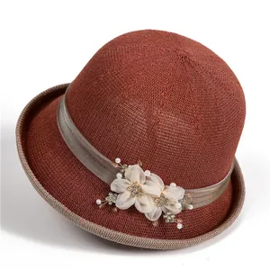 Nahaufnahme eines eleganten dunkelroten Sonnenhuts mit Seidenband und weißen Stoffblumen