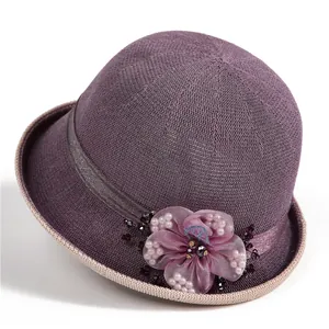 Detail of purple knitted sun hat featuring elegant mesh flower with pearl embellishments