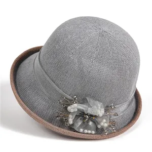 Detail of grey knitted sun hat featuring floral lace applique and elegant pearl accents