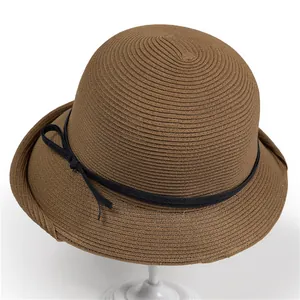 Detail of dark brown woven straw hat texture with black ribbon and side bow accent