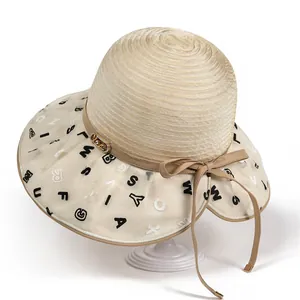 Detail of light beige sun hat showing spiral weave and sheer letter embroidery on brim