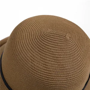 Close-up detail showing the fine concentric woven texture of the brown straw sun hat crown