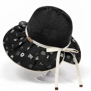 Detail of sun hat showing spiral weave texture, letter print brim, and gold metal buckle