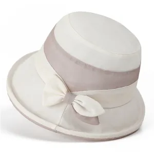 Detail of cream sun hat with pink ribbon bow showing breathable woven texture for summer
