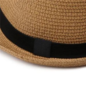 Close-up of light brown woven straw texture and black ribbon band on a sun hat