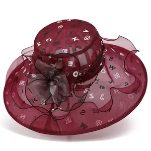 Detail eines burgunderfarbenen Organza-Sonnenhuts mit großer Blume und Buchstabenmuster