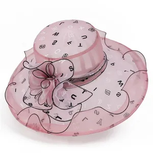 Detailansicht des rosa Organza Sonnenhuts mit Buchstabendruck und großer Blumenverzierung