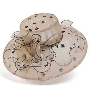 Detail eines eleganten Sonnenhuts in Apricot mit Organza-Blume und Buchstaben-Muster