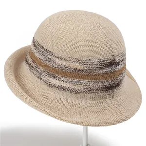 Detail view of a beige knitted cloche hat with textured brown stripes on a stand