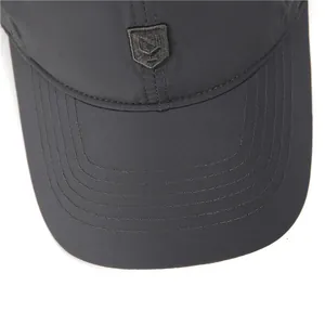 Detail of dark grey quick-dry baseball cap featuring curved brim stitching and shield logo