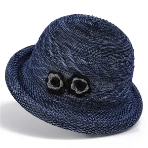 Detail of navy blue knit sun hat featuring delicate crochet flowers and woven texture