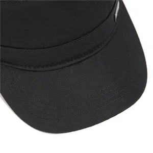 Macro detail of black cotton flat top hat with silver metal logo and stitched brim