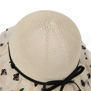 Detail of woven straw crown and sheer mesh brim with black butterfly patterns on sun hat