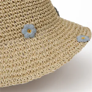 Detailed close-up of handmade woven straw hat featuring delicate blue floral embroidery