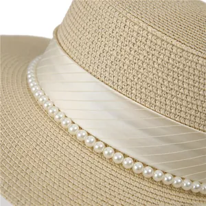 Détail d'un chapeau de paille tissé avec ruban crème et perles élégantes incrustées