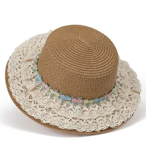 Détail d'un chapeau de paille avec bordure en dentelle et broderie florale colorée