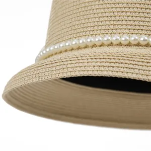 Close-up of woven straw hat featuring detailed pearl band and internal sweatband