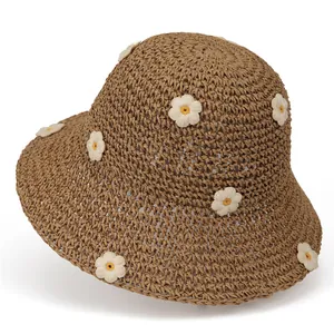 Detail of handwoven brown straw hat featuring delicate white daisy embroidery and texture