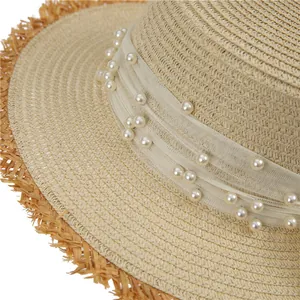 Detailed close-up of straw hat featuring white lace ribbon with elegant pearls and frayed edges