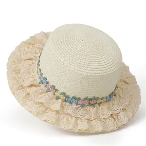 Gros plan du chapeau de paille beige avec dentelle délicate et broderies florales colorées