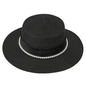 Détail d'un chapeau de paille noir à bord plat avec perles élégantes et ruban en satin