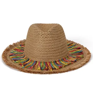 Detail of light brown straw hat featuring colorful rainbow tassel fringe on the brim