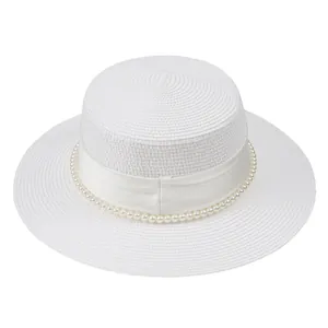 Détail d'un chapeau de paille blanc avec décorations de perles et ruban de satin