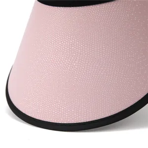Close-up of pink sun hat brim with micro-dot texture and black fabric stitched edging