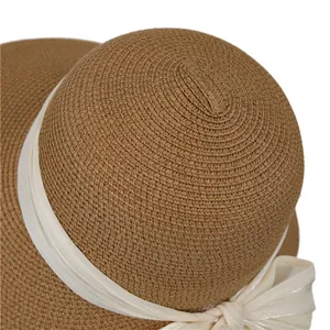 Détail de la texture en paille tressée et du nœud en satin blanc sur le chapeau