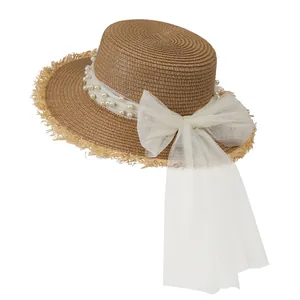 Detail of straw boater hat featuring pearl mesh ribbon and oversized white mesh bow