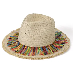 Detail of beige straw hat featuring vibrant colorful tassels and natural frayed edges