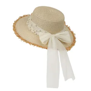 Straw sun hat with flat top, frayed edges, pearl decor and large mesh bow for women