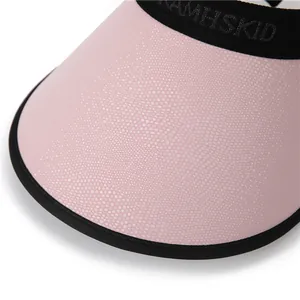 Close-up of pink sun visor featuring pebble texture brim and elastic AMHSKID strap