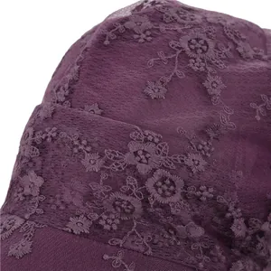 Detailansicht der dunkelvioletten Spitzenstickerei und Blumenstruktur auf der Kappe