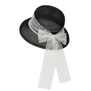 Detail of black straw sun hat featuring elegant white lace bow and pearl chain decoration
