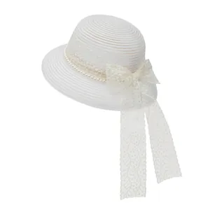 Close-up of white woven straw hat with delicate lace bow, pearls and floral embroidery