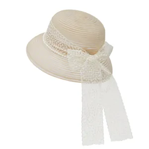 Close-up of elegant beige straw sun hat with white lace ribbon and pearl decoration